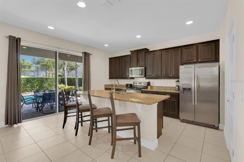 7403 Marker Avenue Kissimmee, FL 34747 - Photo 11 of 49 a kitchen with stainless steel appliances granite countertop a stove a refrigerator a kitchen island a table and chairs in it