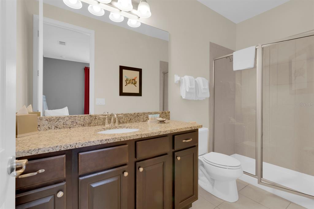 7403 Marker Avenue Kissimmee, FL 34747 - Photo 30 of 49 a bathroom with a granite countertop sink a toilet and a mirror