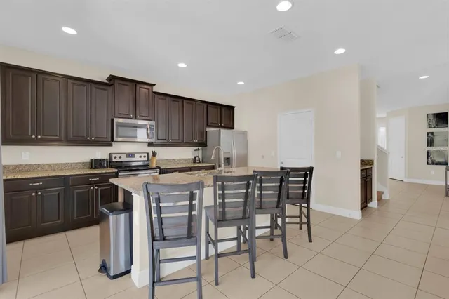 a kitchen with stainless steel appliances granite countertop a stove a sink a microwave a island with a dining table and chairs