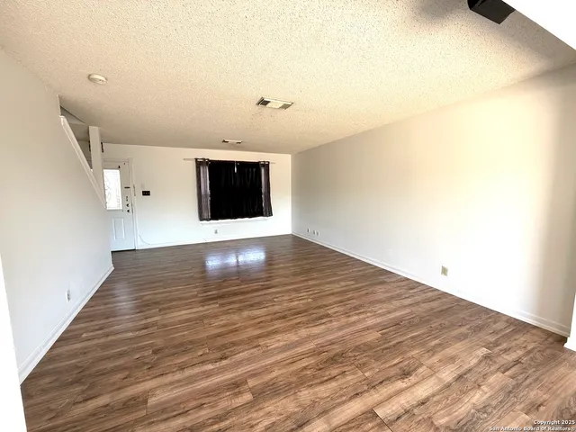 a view of an empty room with wooden floor