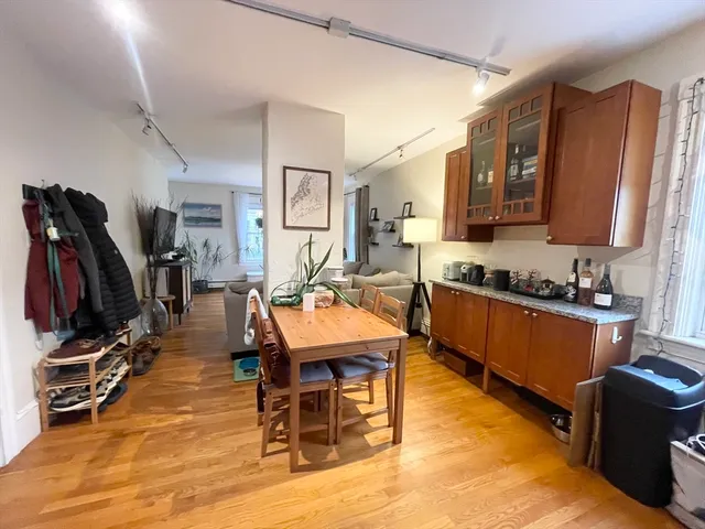 a room with stainless steel appliances lots of furniture and wooden floor