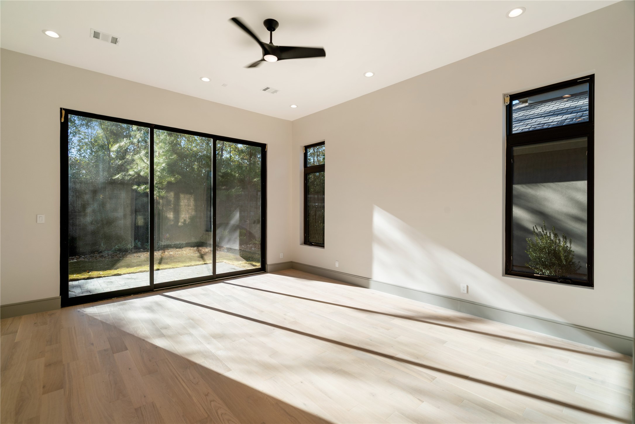 47 Pronghorn Place Spring, TX 77389 - Photo 20 of 48 Bright, spacious room with large sliding glass doors and windows, offering plenty of natural light. Features light wood flooring, neutral walls, and a ceiling fan, creating a modern and airy atmosphere. Ideal for relaxation or as a sunroom.