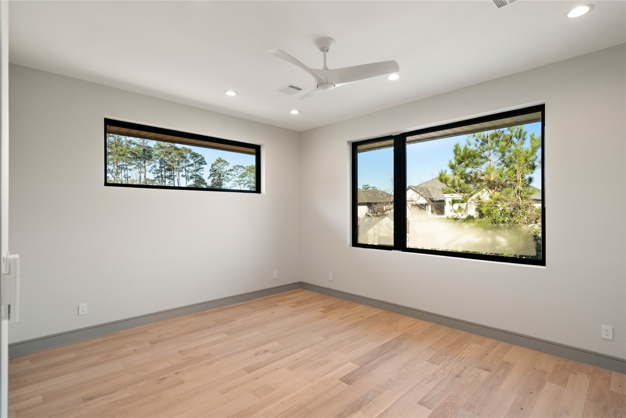 47 Pronghorn Place Spring, TX 77389 - Photo 33 of 48 This bright, spacious room features large windows with scenic views, light wood flooring, recessed lighting, and a ceiling fan, offering a modern and inviting atmosphere.