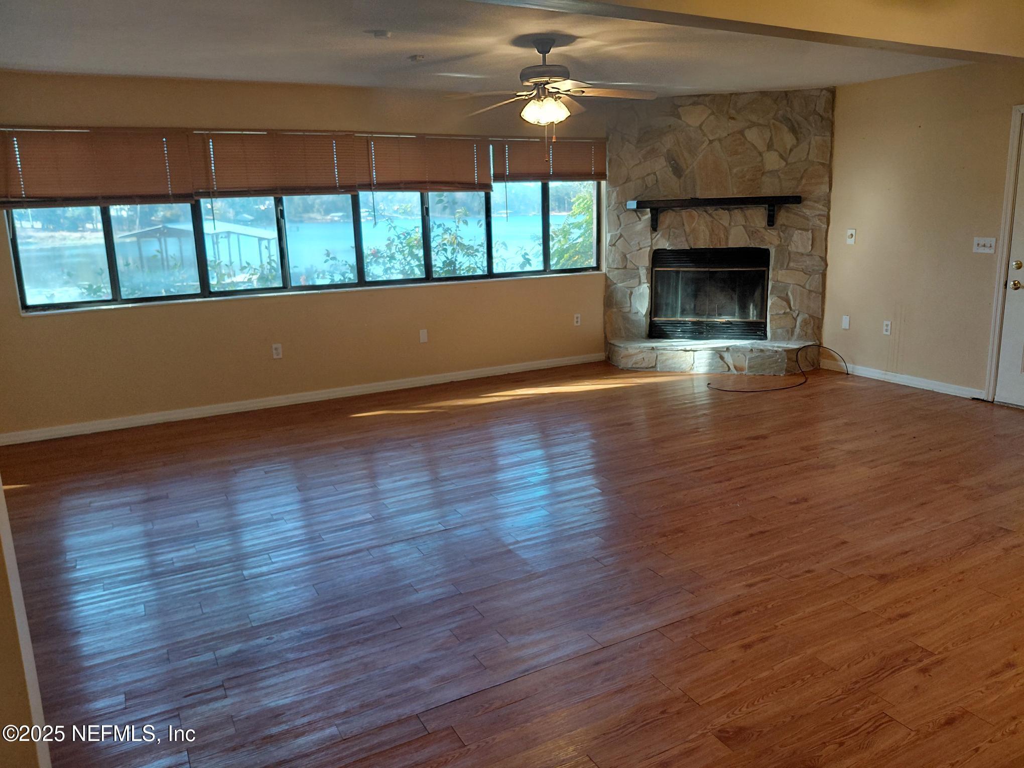 113 Lake Como Point Road Pomona Park, FL 32181 - Photo 23 of 36 an empty room with wooden floor fireplace and windows