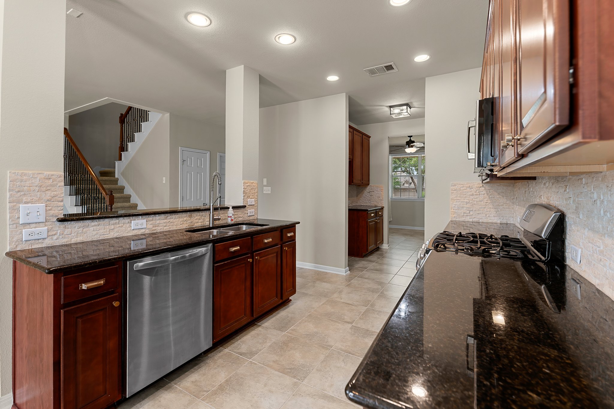 2813 Granite Hill Cove Leander, TX 78641 - Photo 19 of 39 Kitchen with recessed lighting, dark stone countertops, light tile patterned floors, backsplash, and dishwasher - freshly painted