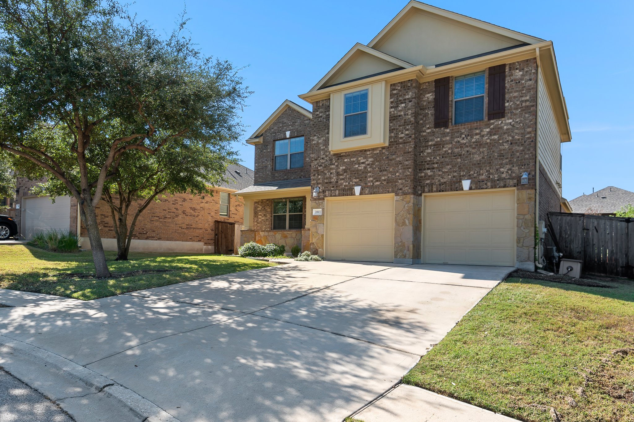 2813 Granite Hill Cove Leander, TX 78641 - Photo 2 of 39 Front of house featuring shaded trees, two car garage entry, and covered porch area.