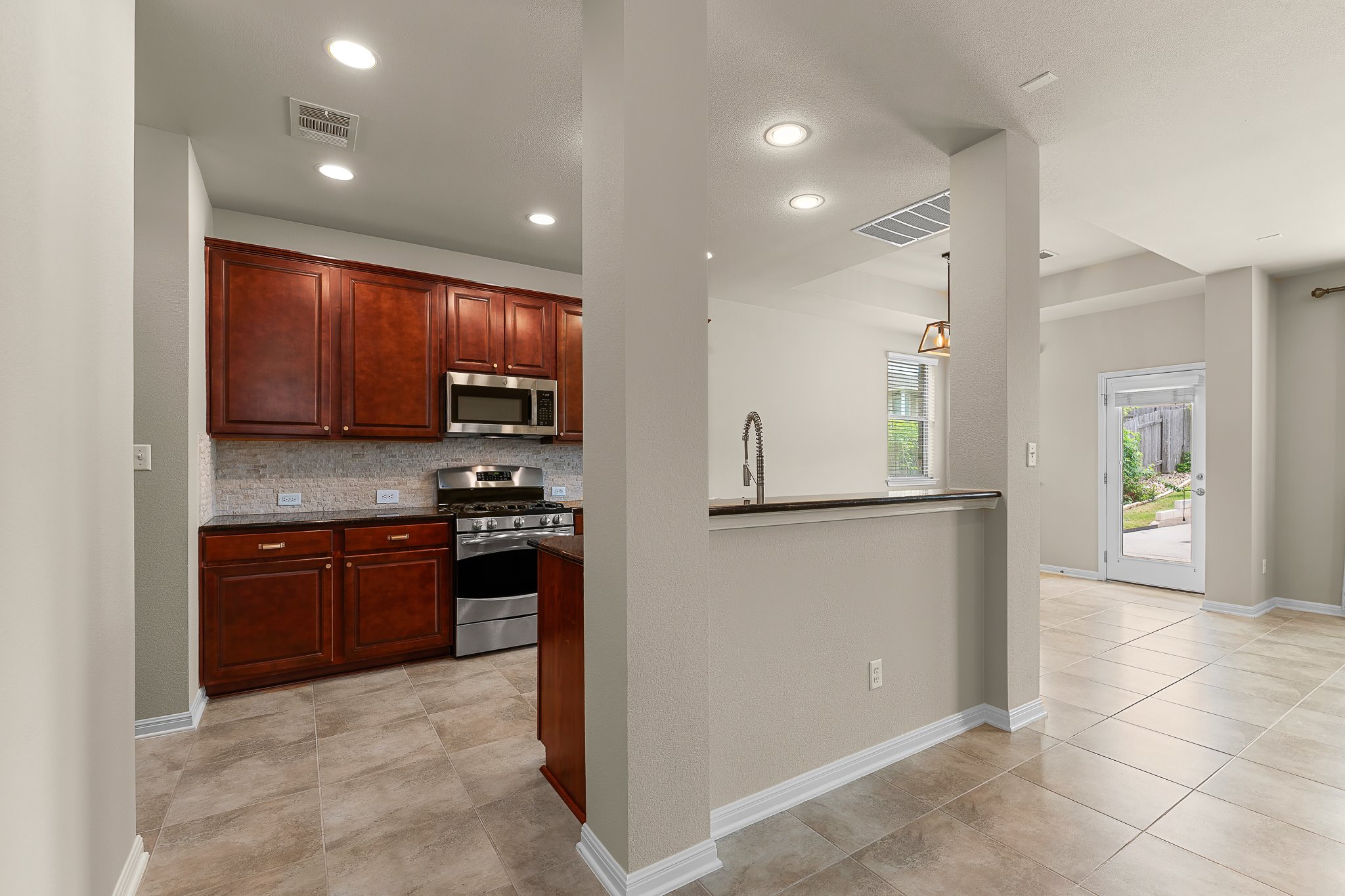 2813 Granite Hill Cove Leander, TX 78641 - Photo 21 of 39 Kitchen with stainless steel appliances, dark stone countertops, tasteful backsplash, recessed lighting, and light tile patterned floors - freshly painted