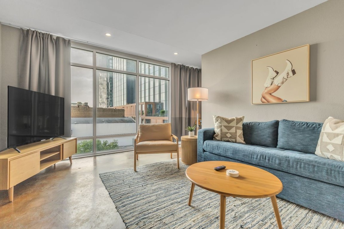 Living room with expansive windows, finished concrete flooring, and recessed lighting