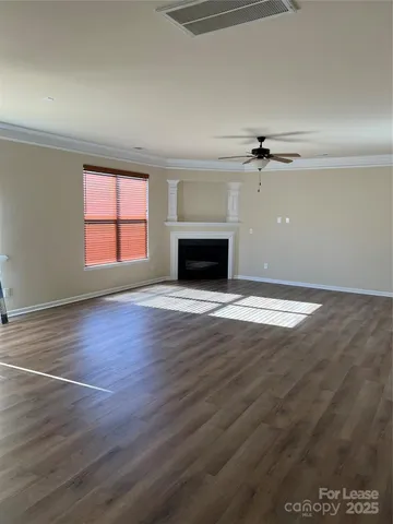 an empty room with wooden floor fireplace and windows