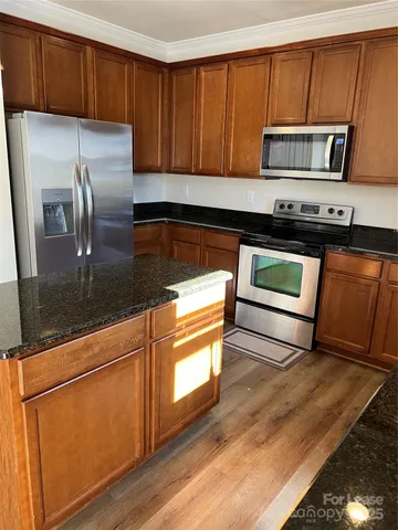 a kitchen with granite countertop wooden cabinets a stove and a refrigerator