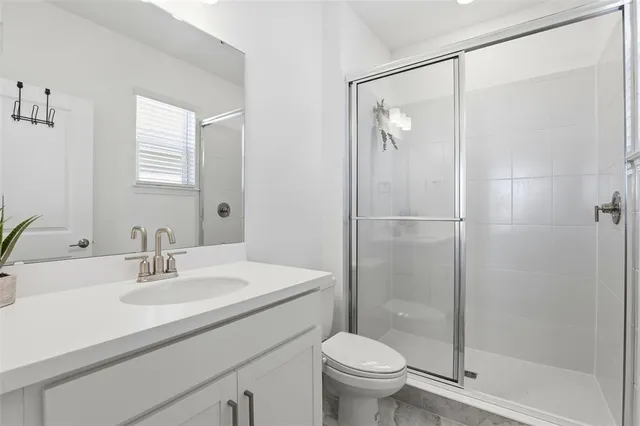 a bathroom with a shower sink vanity mirror and toilet