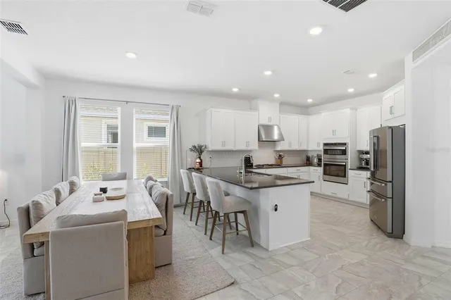 a kitchen with sink a refrigerator and chairs