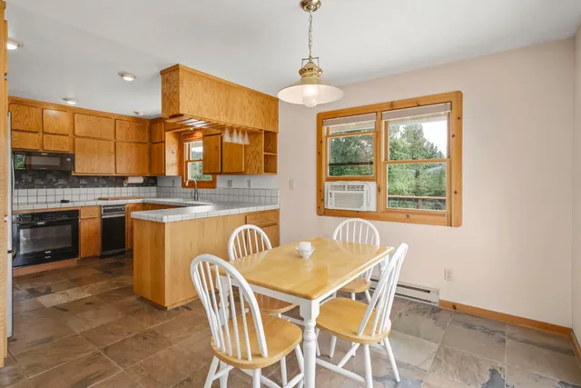 a dining room with stainless steel appliances granite countertop a sink a stove a table and chairs
