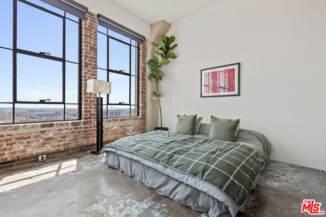 a bedroom with a bed painting on wall and a large window