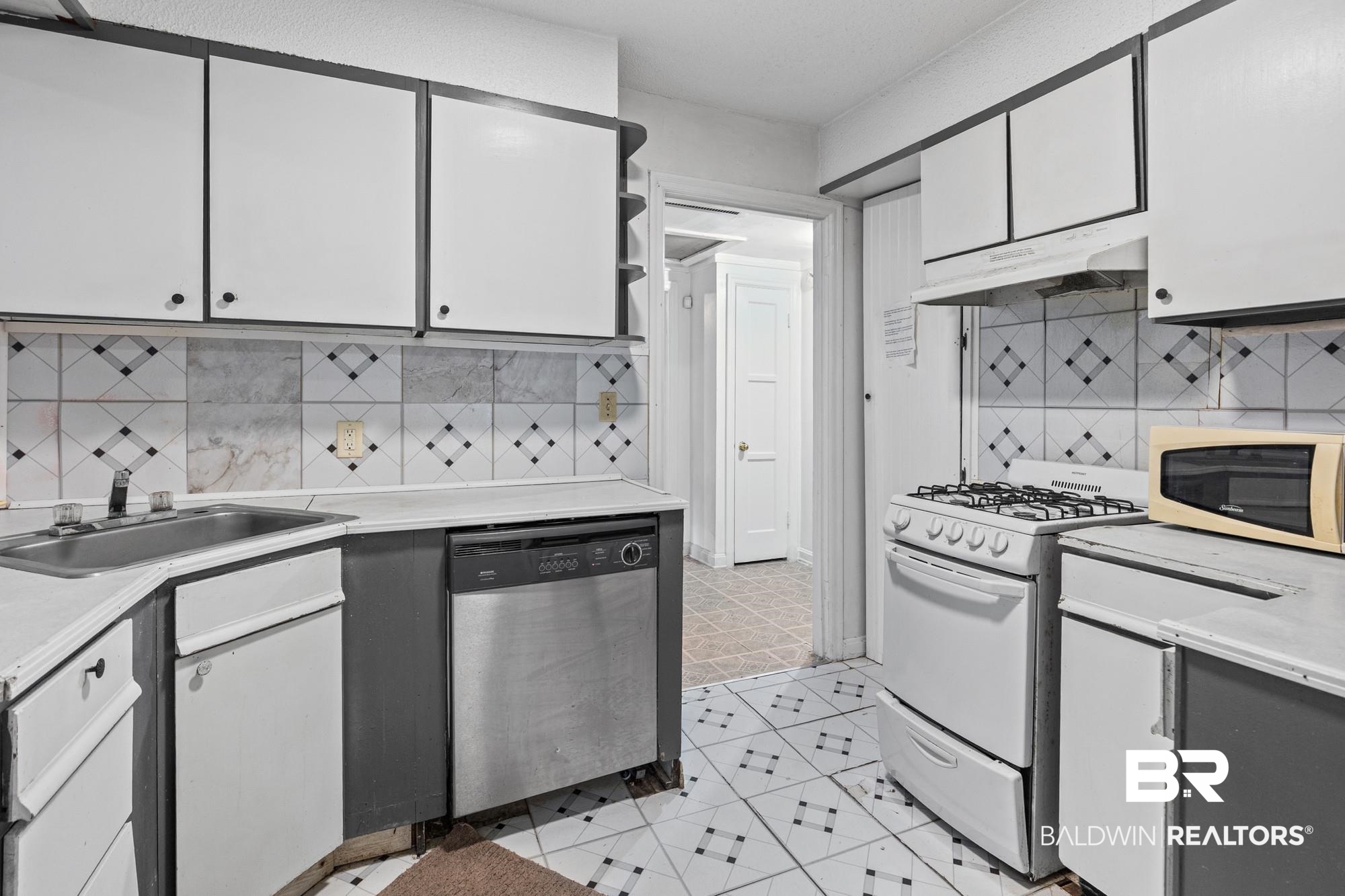 160 Glenn Avenue Mobile, AL 36606 - Photo 3 of 15 Kitchen featuring white cabinetry with dark trim, patterned tile backsplash, stainless steel dishwasher, gas range, and patterned floor tiling