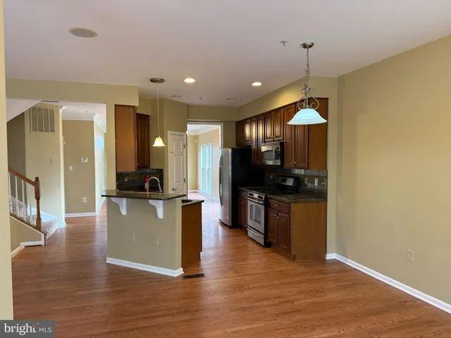 a view of an empty room with wooden floor fireplace and a window