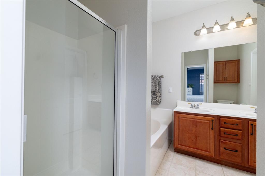 4025 Chisos Rim Trail Fort Worth, TX 76244 - Photo 22 of 40 Bathroom featuring a double vanity with wood cabinetry, a tiled shower enclosure, and an integrated bathtub