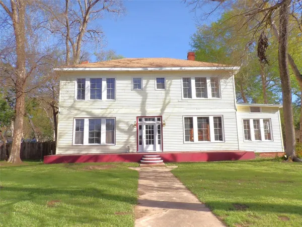 a front view of a house with a yard and trees