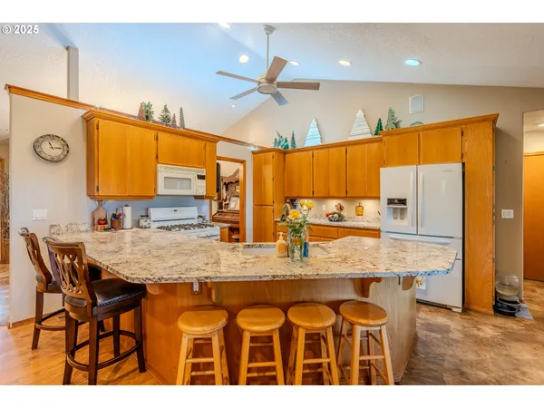a kitchen with stainless steel appliances kitchen island granite countertop a table chairs in it and wooden floors