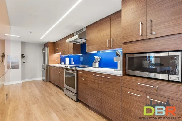 a kitchen with stainless steel appliances kitchen island granite countertop a refrigerator a stove and a wooden floors