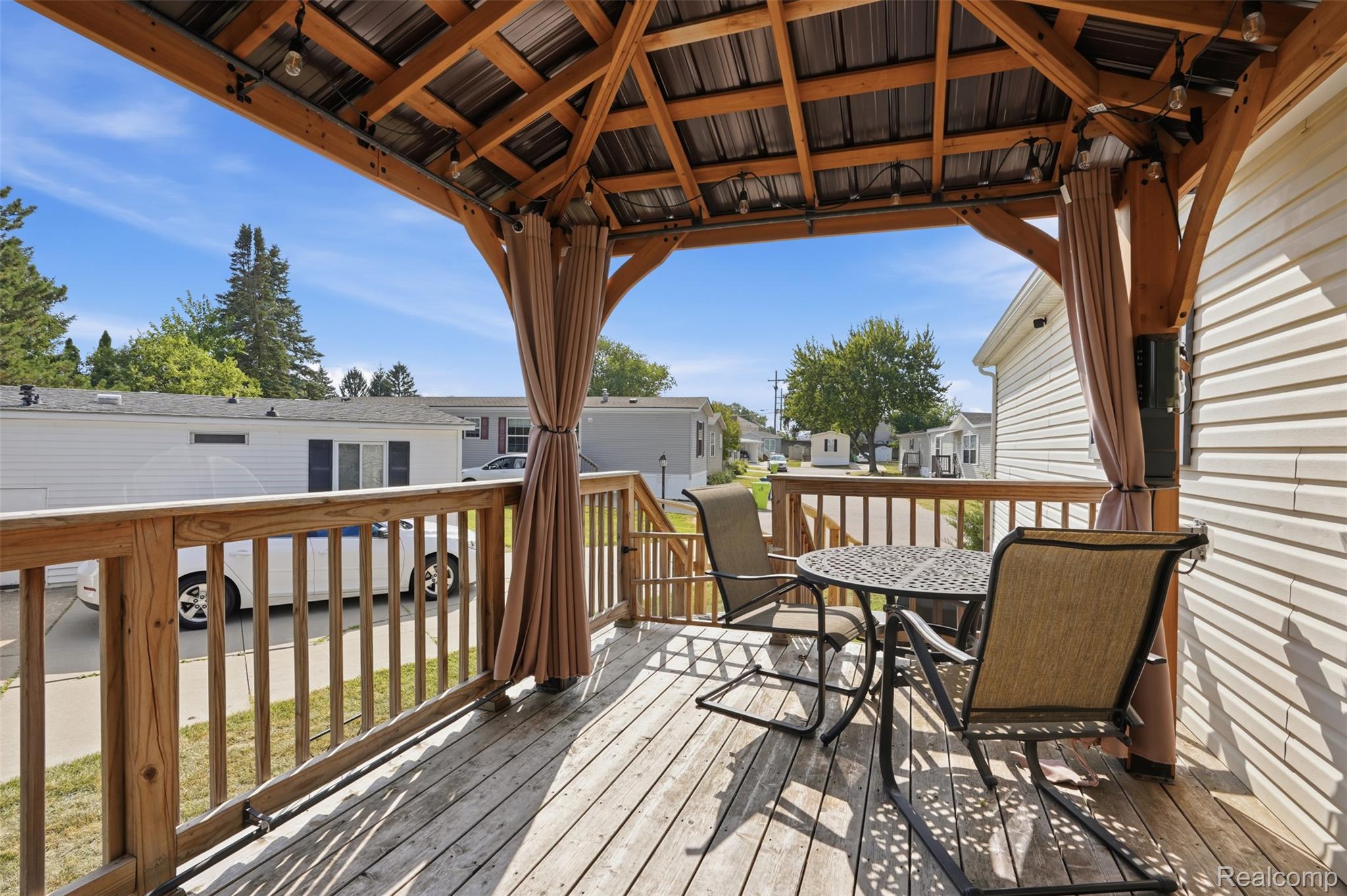 150 Whippoorwill Lane Rochester, MI 48309 - Photo 19 of 28 Covered outdoor deck featuring natural wood flooring and railing, a metal roof, and string lighting
