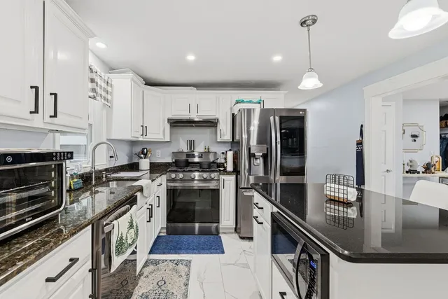 a kitchen with stainless steel appliances granite countertop a sink a stove and a refrigerator