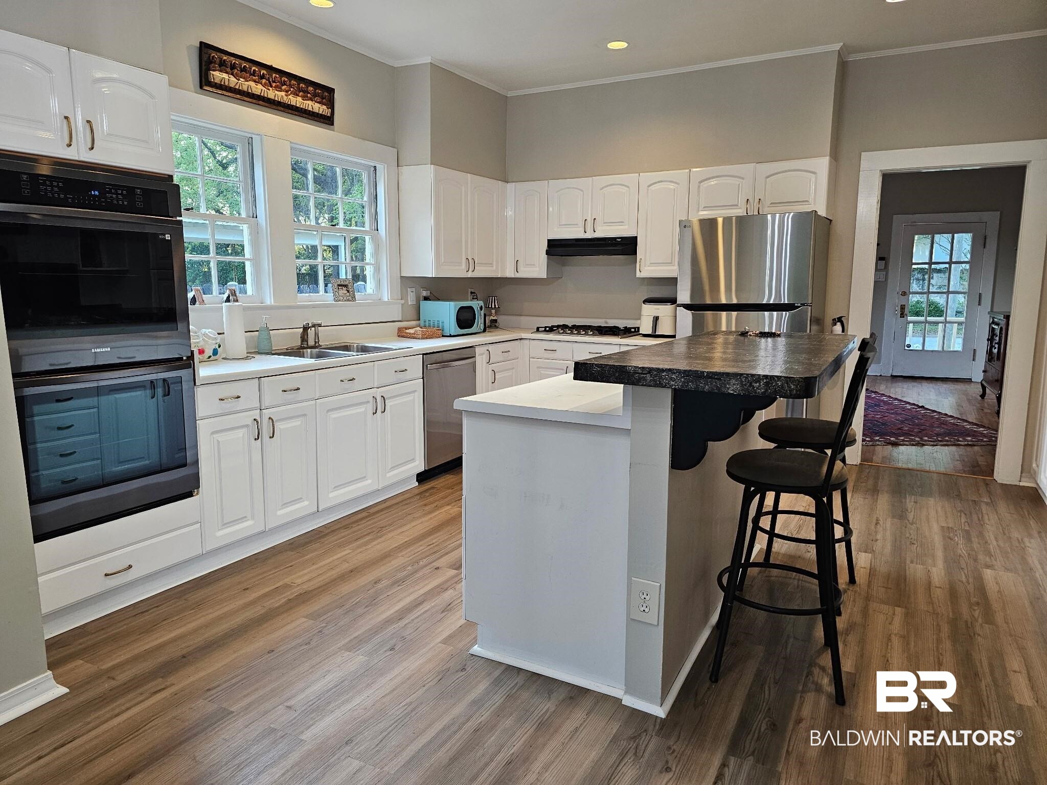 1215 Church Street Mobile, AL 36604 - Photo 8 of 23 Kitchen with a breakfast bar, white cabinets, wood finished floors, and stainless steel appliances