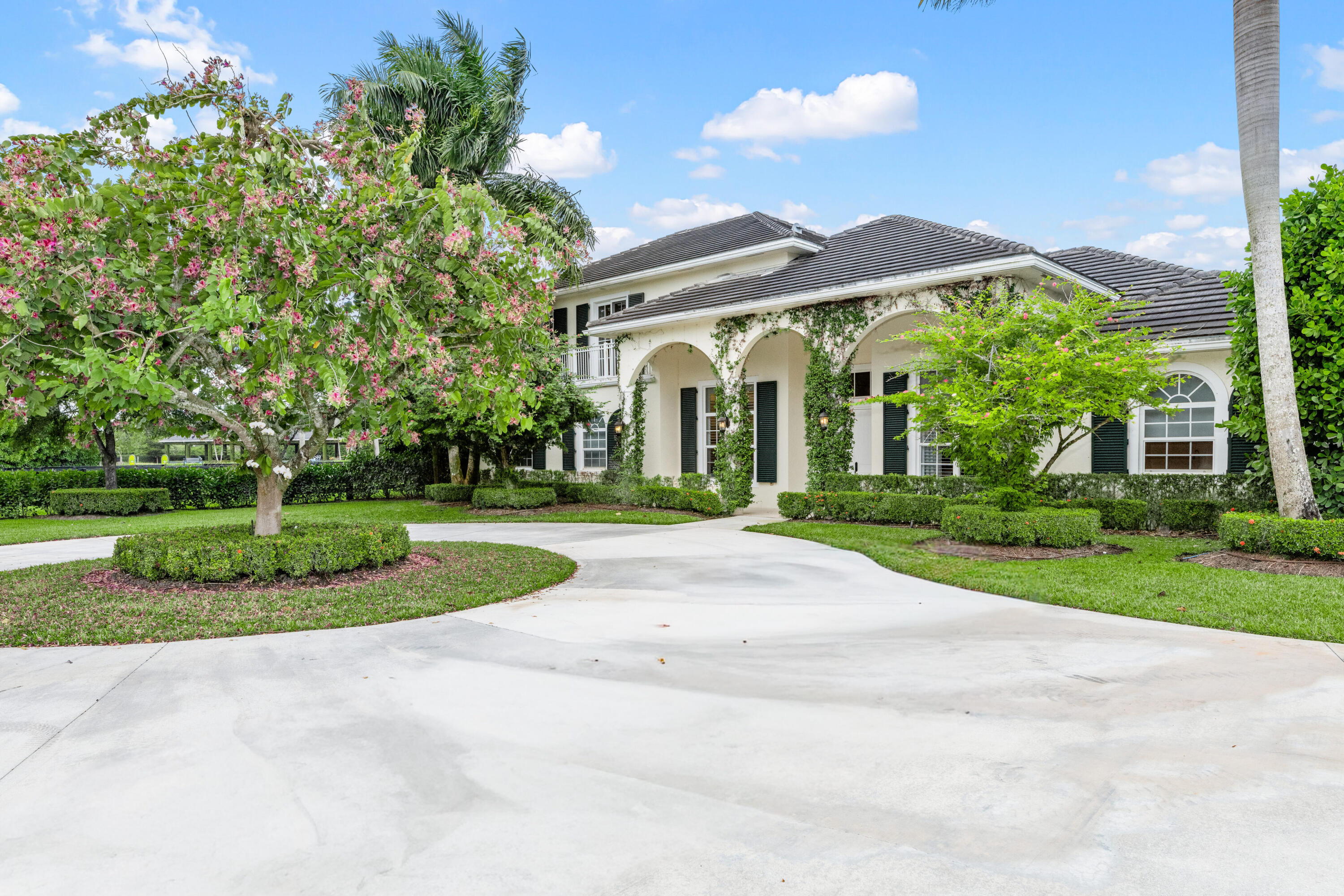 14739 Jumper Road Wellington, FL 33449 - Photo 19 of 124 a view of a white house with a big yard and potted plants