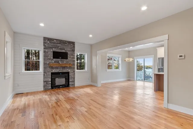 a view of an empty room with wooden floor and a kitchen