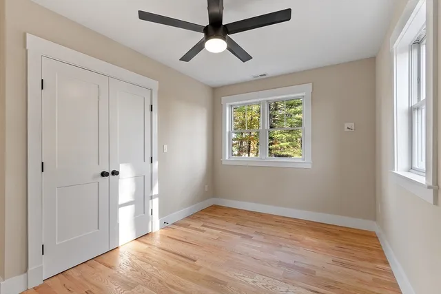 a view of empty room with wooden floor and fan