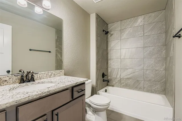 a bathroom with a granite countertop sink a toilet and bathtub