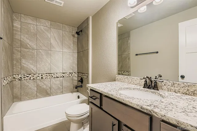 a bathroom with a granite countertop sink a toilet and shower
