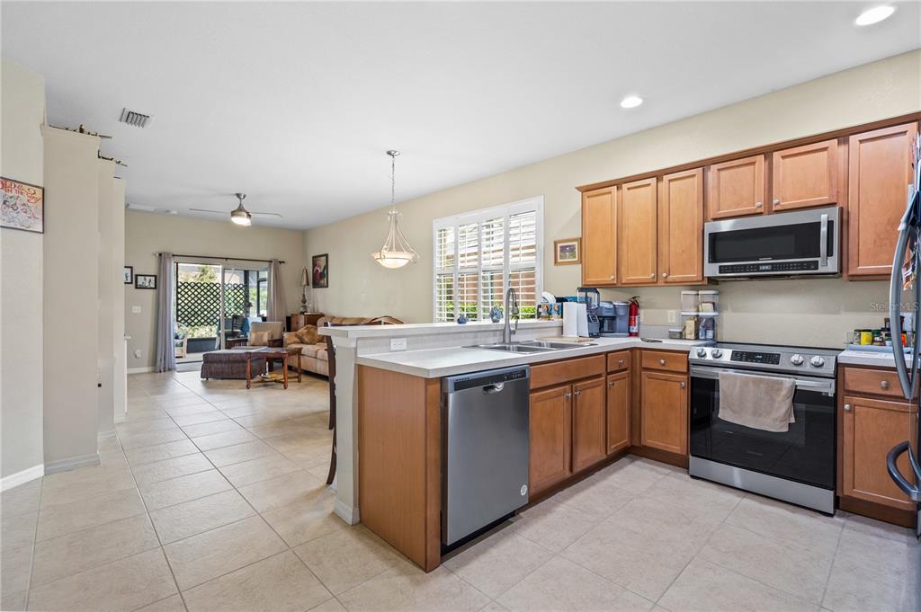 11815 Tempest Harbor Loop Venice, FL 34292 - Photo 7 of 63 a kitchen with stainless steel appliances granite countertop a stove top oven a sink dishwasher a dining table and chairs with wooden floor