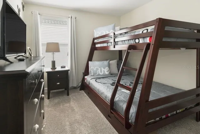 a bedroom with a bunk bed and a flat tv screen on the dresser