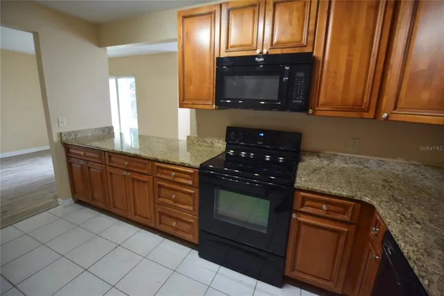 a kitchen with granite countertop a stove microwave and sink