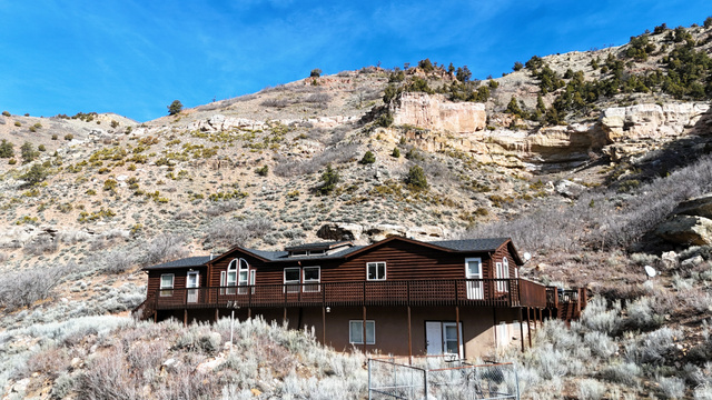 7500 Spring Canyon Road Helper, UT 84526 - Photo 2 of 83 Back of property featuring a mountain view, log veneer siding, and roof mounted solar panels