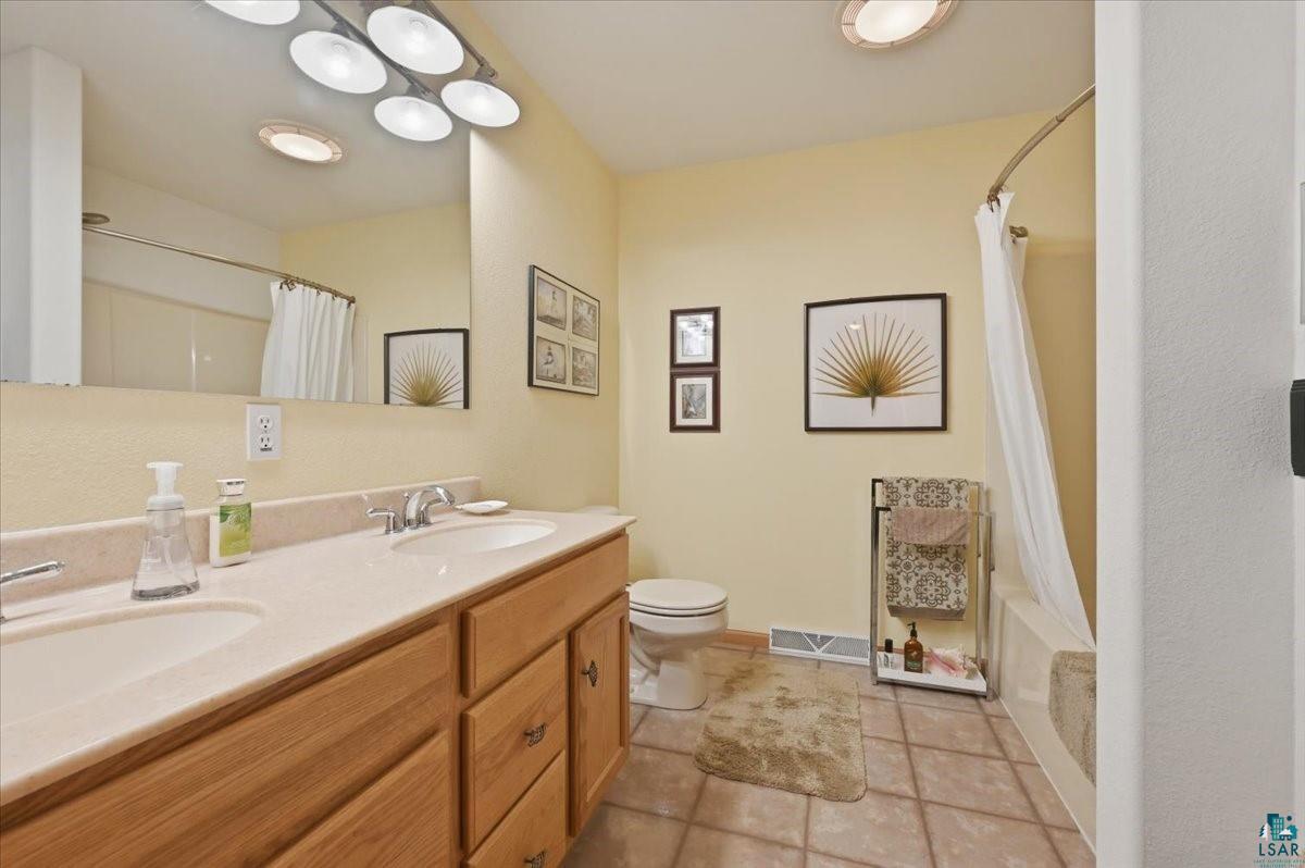 8162 South Dowling Road West Superior, WI 54880 - Photo 8 of 15 Bathroom featuring a double vanity with light wood cabinetry, a neutral countertop, and dual integrated sinks
