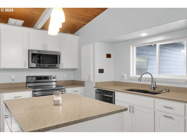 a kitchen with kitchen island granite countertop a sink a stove top oven a granite counter space and cabinets