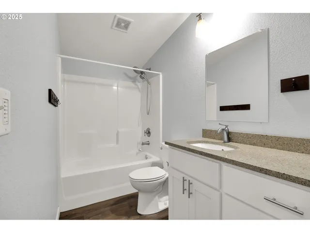 a bathroom with a granite countertop sink toilet a mirror and bathtub