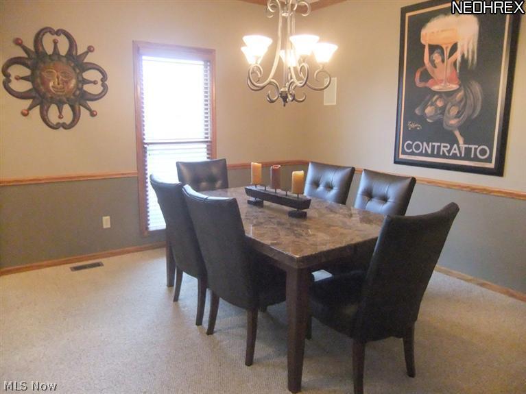3795 Stonebridge Boulevard Akron, OH 44321 - Photo 4 of 24 The formal dining room features neutral carpet, chair rail trim and crown molding.