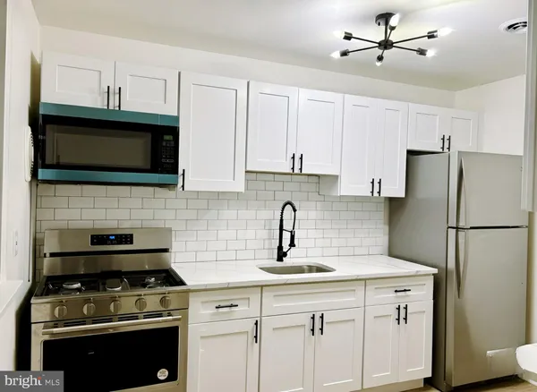 a kitchen with cabinets stainless steel appliances a sink and wooden floor