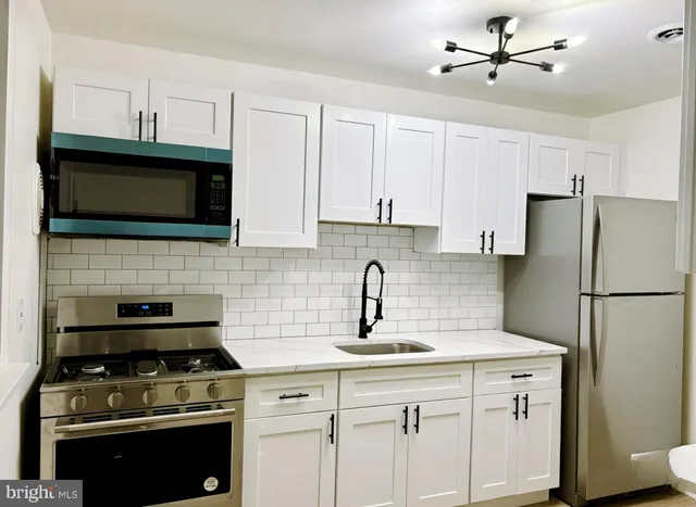 a kitchen with cabinets stainless steel appliances a sink and wooden floor