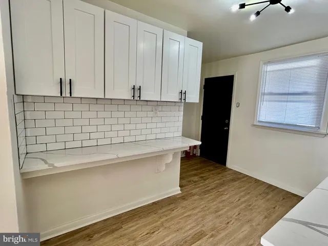 a view of kitchen with stainless steel appliances wooden floor and cabinets