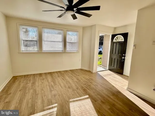 a view of an empty room with wooden floor and a window