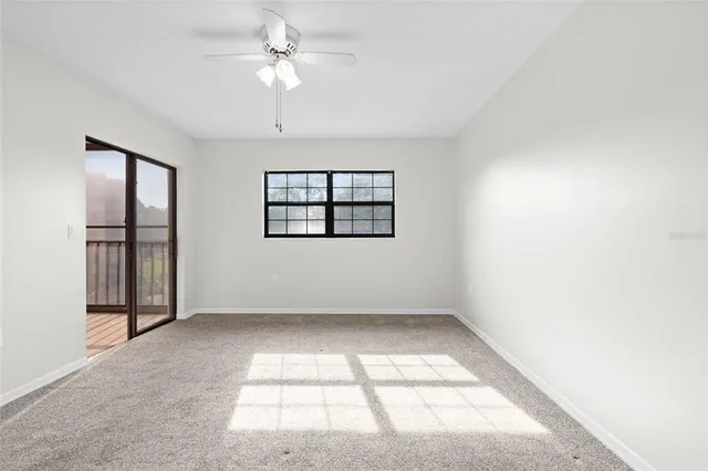 an empty room with windows and ceiling fan