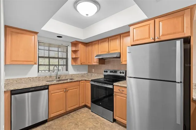 a kitchen with stainless steel appliances granite countertop a refrigerator sink stove and cabinets