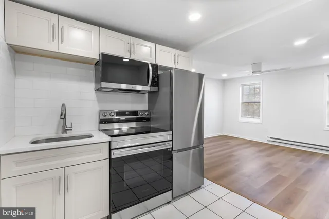 a kitchen with stainless steel appliances white cabinets and a stove top oven