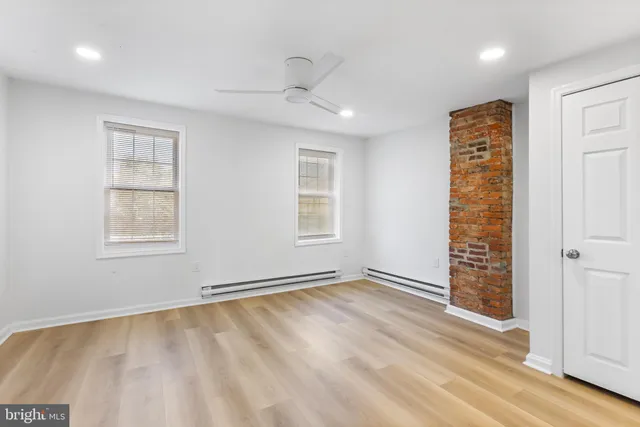 a view of an empty room with window and wooden floor