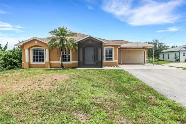 a front view of a house with a yard and trees