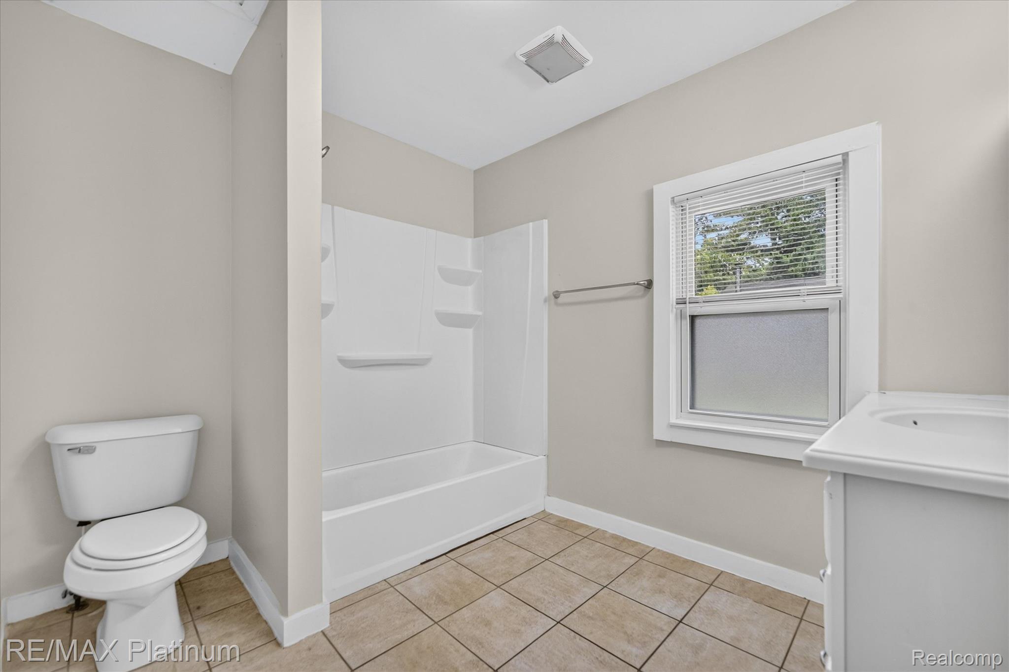501 Kaiser Road Gregory, MI 48137 - Photo 18 of 27 Bathroom featuring a tub and shower combination with integrated shelving, a single vanity with an integrated sink, a toilet, and a window with blinds